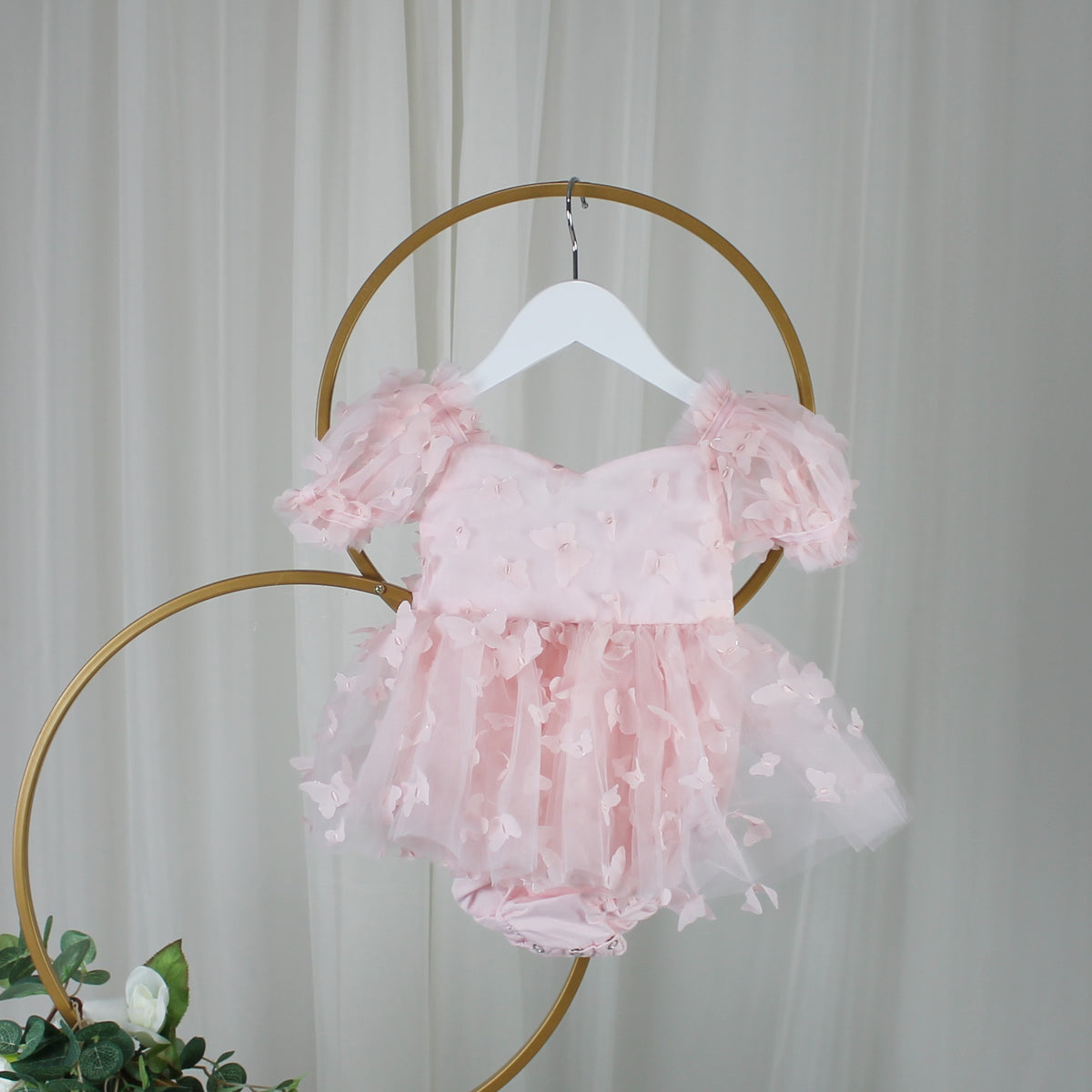 Light pink butterfly dress with puff sleeves on a hanger