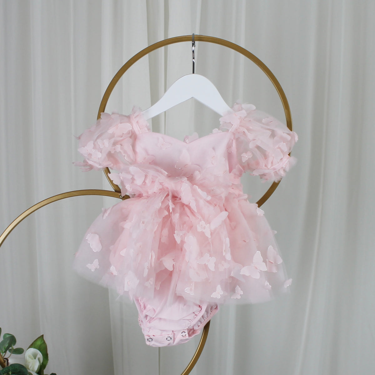 Back of light pink butterfly tulle dress on a hanger